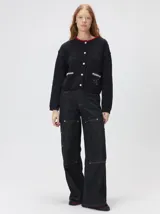 Cardigan de algodón grueso en color rojo, con cuello redondo y cierre frontal de botones grandes. Presenta bolsillos cuadrados en el bajo con detalles de pelo sintético en los bordes y logo bordado en uno de ellos. Posee puños y ruedo elastizados con diseño holgado.