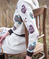 Sweater de punto color marfil con bordados artesanales en relieve de motivos paisley y florales en tonos morados, celestes y marrones. Posee cuello alto, puños y dobladillo en tono marrón oscuro.