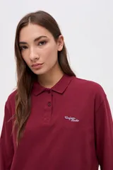 Remera tipo polo de manga larga en color beige, confeccionada en algodón pesado con textura suave. Presenta cuello clásico, cierre frontal con botones y un pequeño bordado en el pecho. Posee puños en las mangas y un corte relajado.