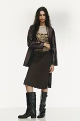 Falda corta tipo pareo, color marrón oscuro, confeccionada en tejido satinado con lazada ajustable en el lateral.