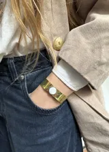 Set de accesorios compuesto por un collar, un brazalete y dos pares de aros, todos elaborados en bronce, presentados en un sobre de cuero marrón tipo gamuza.
