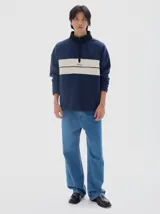 Buzo de felpa azul marino con interior de friza, cuello alto negro y media cartera con cierre. Presenta un corte horizontal en el pecho en color beige con el logo "PASTICHE" bordado en negro.