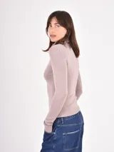 Polera de tejido de punto fino, con cuello alto doblado y mangas largas. Presenta un diseño ajustado al cuerpo con terminaciones acanaladas en puños y ruedo.