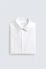 Camisa blanca de corte slim fit, confeccionada en tejido de algodón. Presenta cuello italiano, manga larga con puño abotonado y cierre frontal de botonadura.
