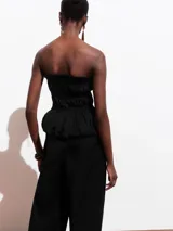 Top negro strapless con cuerpo fruncido tipo smock y bajo abullonado con acabado peplum.