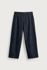 Pantalón barrel fit de hombre, confeccionado en denim de algodón azul oscuro sin lavado. Presenta cintura con pliegues frontales, bolsillos laterales y cierre con cremallera y gancho oculto.