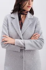 Tapado de paño gris con apliques de hotfix plateados. Presenta un diseño de corte regular con cuello solapa, cierre frontal con botón, bolsillos laterales con tapa y forrería interna a tono.