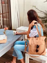 Cartera tipo tote bag color beige con textura símil cocodrilo, doble asa corta y correa larga extraíble y ajustable. Tiene dos bolsillos externos grandes y cierre superior con botón a presión.