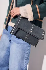 Cartera bandolera negra con tachas plateadas, confeccionada en gamuza vegana.