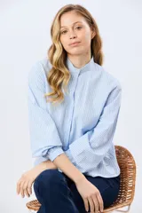 Camisa rayada de manga larga, confeccionada en algodón, con cuello mao y cierre frontal de botones.