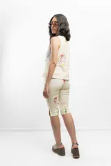 Pantalón capri color crema con estampado de rostros femeninos, flores y textos en colores.