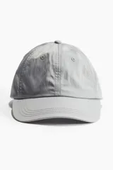 Gorra de sarga color gris con ojales bordados, costuras pespunteadas en la visera y diseño clásico de seis paneles.