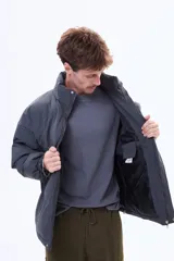 Campera puffer negra de corte estándar, con cuello alto, cierre frontal completo y puños elásticos.