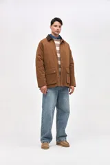 Campera de gabardina color marrón con cuello de pana en tono oscuro. Presenta cierre frontal con botones a presión, bolsillos laterales con solapa y diseño de calce clásico.