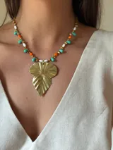 Collar corto con cuentas de cristal checo en turquesa, naranja y blanco, mostacillas doradas y dije de alpaca texturizada en forma de hojas. Se cierra con cadena de acero quirúrgico para regular el largo.