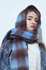 Bufanda oversized de textura suave con diseño a cuadros en tonos marrón y azul.
