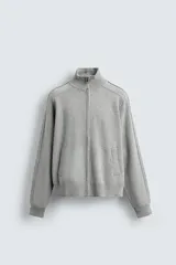 Chaqueta de punto compacto con mezcla de algodón, corte relajado, cuello subido, manga larga, bolsillos laterales de vivo y cierre frontal con cremallera.