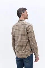 Camisa de manga larga confeccionada en viyela de algodón con diseño a cuadros en tonos verde oscuro. Presenta cuello clásico, cierre frontal con botones y bolsillo aplicado en el pecho.