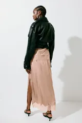 Falda midi color rosado, confeccionada en tejido fluido de satén con cremallera lateral oculta. Presenta un bajo festoneado de encaje y abertura pronunciada en un lateral.