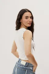 Top crop negro de calce ajustado, con escote redondo, diseño sin mangas y detalles de ojales metálicos decorativos en los hombros.