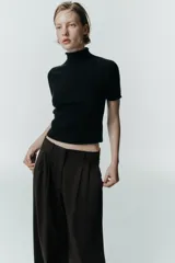 Pantalón de tiro medio con pinzas en el delantero, trabillas para cinturón, bolsillos laterales y tapetas decorativas en la parte trasera. Presenta un cierre frontal con cremallera, botón interior y gancho metálico.