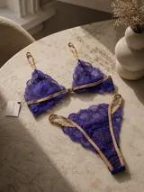 Conjunto de lencería de encaje violeta con tiras elásticas en tono tostado, compuesto por un soutiene bralette y bombacha a juego.