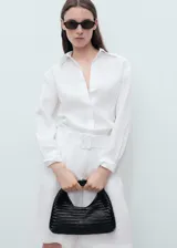 Camisa blanca oversize de lino, con cuello camisero, manga larga con puños abotonados y cierre frontal con botones.