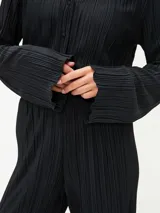 Camisa negra con textura plisada, cuello clásico, escote en V y mangas largas.