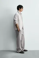 Camisa de corte relajado confeccionada en tejido de algodón con textura, diseño a rayas verticales, cuello abotonado, manga larga con puños y bolsillo de plastrón en el pecho.