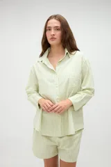 Camisa de manga larga de algodón, con diseño a rayas en tonos azules y morados, calce holgado, cuello camisero, cierre frontal con botones y un bolsillo aplicado en el pecho.