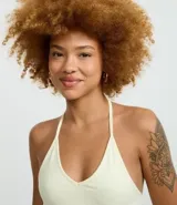 Top cropped de algodón color amarillo pálido, con escote en V pronunciado y tirantes finos que se atan en la nuca (estilo halter). El tejido es acanalado.