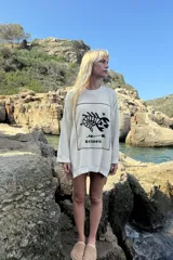 Sweater de punto oversize color crudo, con cuello redondo y diseño bordado a mano en el frente representando al signo Cáncer con un cangrejo, un corazón y una estrella.