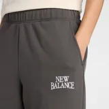 Pantalón de jogging New Balance de tiro alto, con corte holgado y pernera barrel. Presenta cintura elástica con cordón interno, bolsillos laterales y el logo de la marca estampado en la pierna.