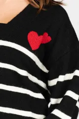 Saco negro con rayas horizontales blancas, escote en V, cierre con botones y un corazón rojo bordado en el pecho.