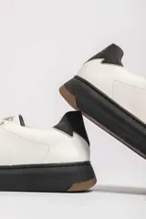 Zapatillas urbanas blancas con detalle azul en el talón y suela de goma.