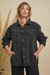Campera de jean color negro con diseño de tachas metálicas plateadas distribuidas en el cuello, los bolsillos frontales y a lo largo de la parte delantera. Cuenta con cierre frontal de botones metálicos y mangas largas.