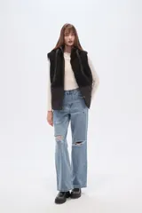 Chaleco con capucha, diseño bicolor que combina textura de corderito en la parte superior y material técnico liso en la parte inferior. Cuenta con cierre frontal y botones a presión.