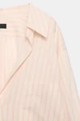 Camisa de mezcla de viscosa, color beige con rayas verticales rosadas, cuello solapa, manga larga con puños anchos, bajo redondeado y cierre frontal con botones.