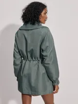 Campera larga color verde con cuello acanalado, cierre de doble sentido, bolsillos de parche grandes, cintura interior ajustable y puños con borde con volados.