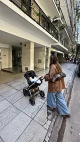 Cartera tipo baguette confeccionada en cuero marrón, con diseño estructurado y alargado, manijas largas y detalles metálicos en la unión de las asas.