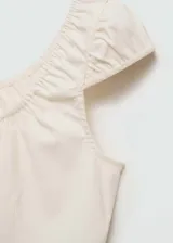 Top color crema con escote cuadrado, mangas cortas abullonadas, lazo decorativo en el frente, cierre frontal con botones y diseño entallado con detalles fruncidos.