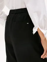 Pantalón de traje de corte recto, confeccionado en una mezcla de lino y lyocell. Presenta un diseño con cierre de cremallera oculta, gancho, cintura elástica en la parte trasera y bolsillos traseros de parche.