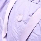 Bolso deportivo de gran capacidad en color lila, confeccionado en material textil con acabado arrugado. Cuenta con doble asa superior, correa ajustable y desmontable, y compartimento principal con cierre doble. Incluye correas en la base para sujetar accesorios y una bolsa interior desmontable.