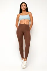 Calza deportiva de talle alto color marrón, con diseño ajustado y costura frontal.