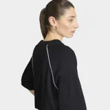 Remera Adidas de corte oversize, color negro, con cuello redondo y mangas cortas. Presenta el logo del Trifolio de la marca bordado en contorno blanco en el centro del pecho y detalles de líneas blancas en las costuras de las mangas.