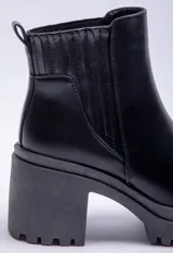 Bota de caña baja color negro, con elástico lateral, punta redonda y taco plataforma.