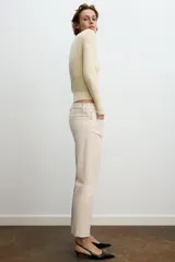 Jeans de mezclilla azul claro, tiro medio, corte recto y ligeramente acampanado en el bajo. Presenta cinco bolsillos y cierre frontal con cremallera y botón metálico.