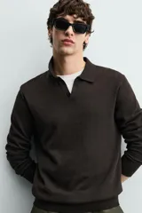 Sweater polo de punto de mezcla de algodón en color negro, con cuello solapa, abertura frontal y mangas largas con acabado en rib.