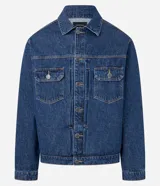 Campera de jean azul oscuro, estilo clásico, con cuello inglés, cierre frontal de botones metálicos y dos bolsillos de parche con tapa y botón en el pecho. Presenta costuras marcadas en color naranja.