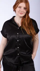 Camisa de manga corta con cuello camisero y botones nacarados. La tela es negra con un patrón de rayas verticales en relieve, con un acabado satinado.